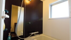 A bathroom with a bathtub, a shower, a mirror, and a window. - Mr. Kinjo Violette Kukomae (Naha)