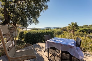 A patio with wicker furniture, a table with a tablecloth, and a view of the landscape.