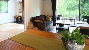 Een moderne woonkamer met een bank, salontafel en een groot raam met uitzicht op groen.
