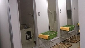 Un baño con tres lavamanos, cada uno con un espejo y una cesta verde.