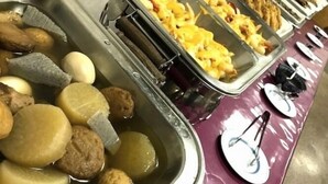 Un bufé con diversos alimentos, incluyendo albóndigas, papas y comida frita.