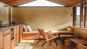 A cozy kitchen with wooden cabinets, a built-in bench, and a large window offering a view of the outdoors. - Secret Break Isumi (Isumi)