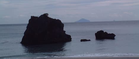 A beach with large rock formations and a distant mountain.