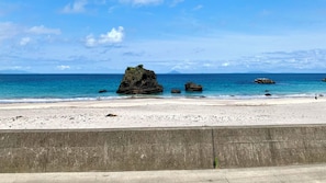 A beach with white sand, a concrete barrier, and rocky formations in the water. - Izu Shimoda Minshuku Sangenya (Shimoda)