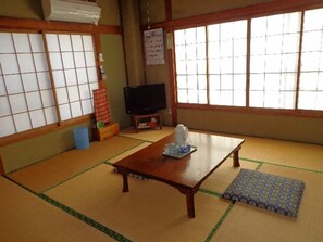 A traditional Japanese room with tatami flooring, a low wooden table, a television, and shoji screens. - Izu Shimoda Minshuku Sangenya (Shimoda)