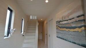 A hallway with a staircase, a large abstract painting, and a window with cotton swabs. - Enico. Mt. Fuji Peace (Fujikawaguchiko)