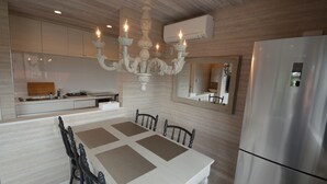 A modern kitchen with a dining table, chairs, a chandelier, and a refrigerator. - Enico. Mt. Fuji Peace (Fujikawaguchiko)