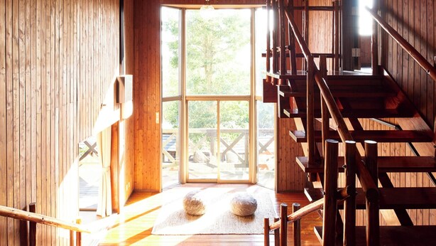 Un interno in legno con una scala, ampie finestre e vista sull'esterno.