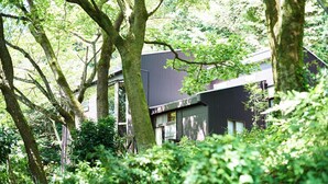 Un edificio moderno con ampie vetrate e facciata scura, immerso nel verde.