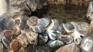 A stone wall with a mosaic pattern and a water feature. - Shoraku Ryokan (Ozu)