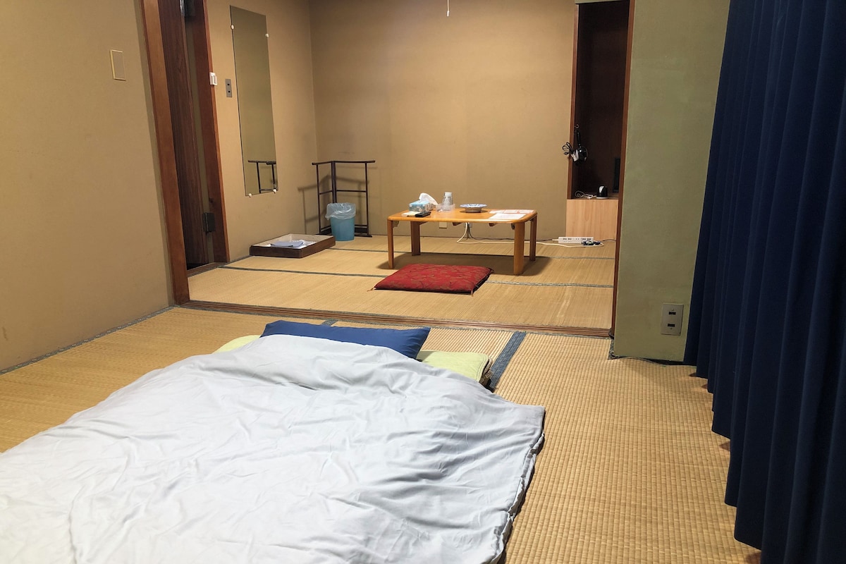 A hotel room with a bed, a small table, a chair, and a mirror.