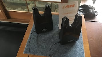 A wooden table with a blue mat, two black shoe dryers, and a sign in Japanese.