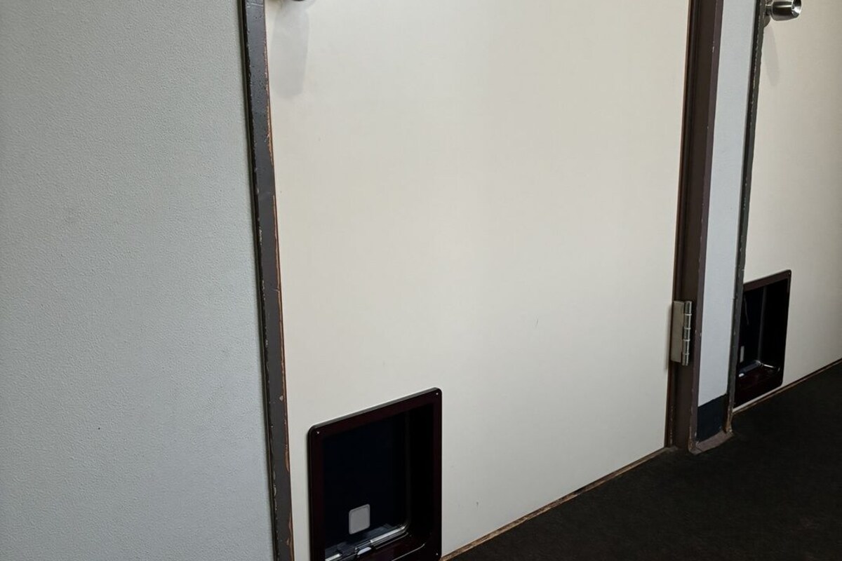 Una puerta con mirilla y un panel de intercomunicador pequeño y de color oscuro.