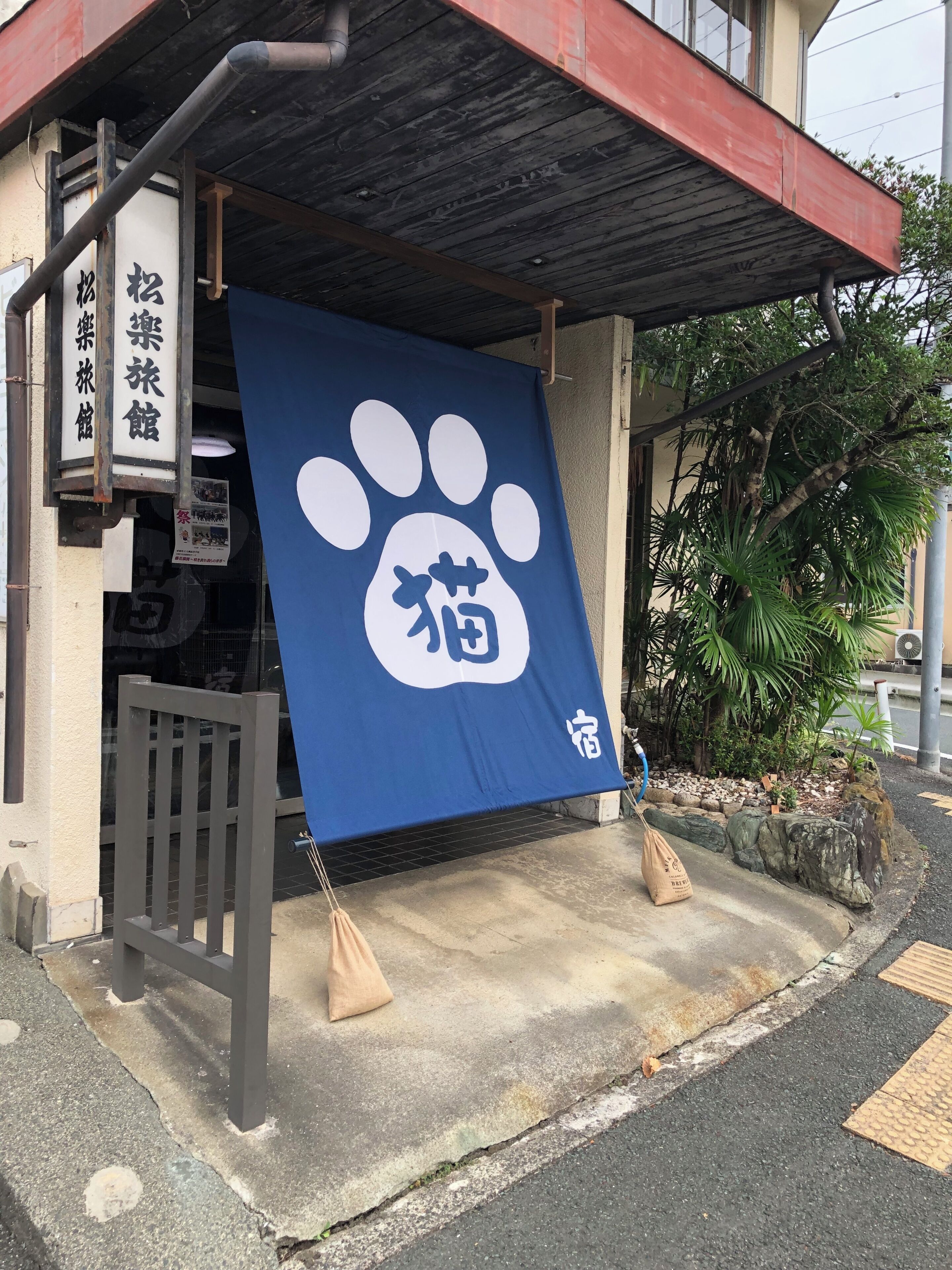 A building entrance with a blue banner featuring a white paw print and Japanese characters.