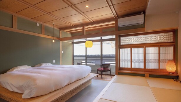 Ein traditioneller japanischer Raum mit Tatami-Boden, einem hölzernen Bett, Blick durch Shoji-Schirme und einer hängenden Papierlaterne.