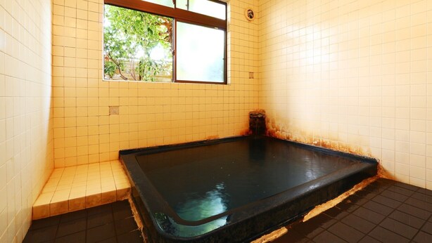 Un cuarto pequeño con baldosas, una bañera, una ventana y una puerta.