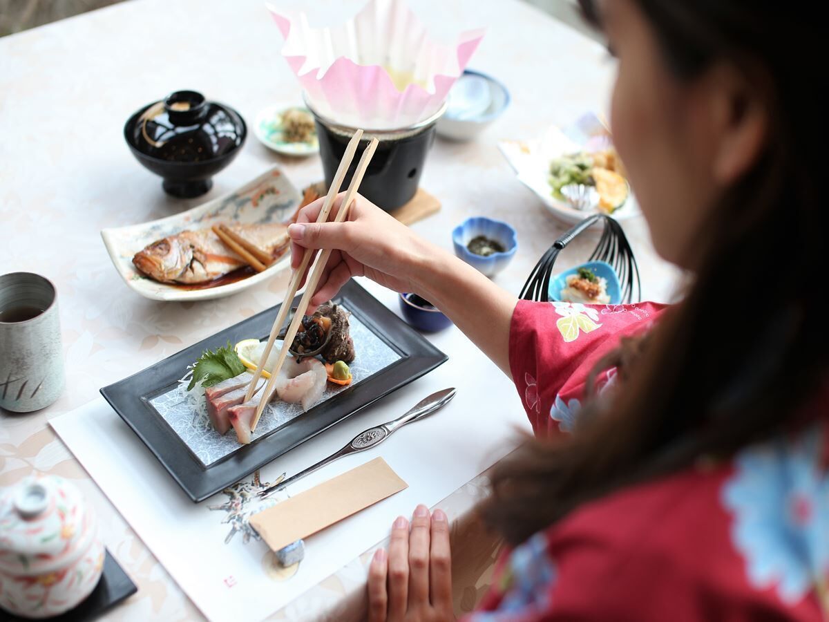 A dining table with various dishes, chopsticks, and a teapot.