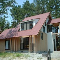 Una casa moderna de dos pisos con techo inclinado, ventanas grandes y fachada de madera.