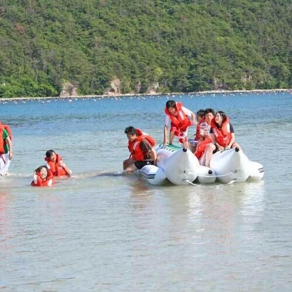 Un grupo de personas en un bote sobre un lago, con una orilla boscosa al fondo.