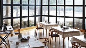 A dining area with large windows, tables, and chairs. - Oki Island Resort Island Park Hotel (Okinoshima)