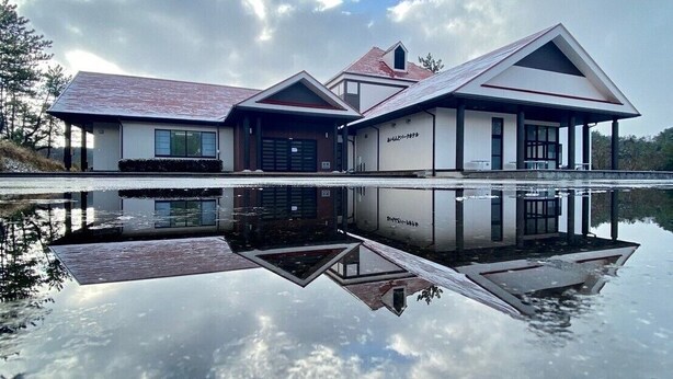 A modern house with a reflective pool in front, surrounded by trees and a cloudy sky. - Oki Island Resort Island Park Hotel (Okinoshima)
