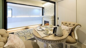 A room with a fireplace, a round table with a kettle, and a sofa. - Guest Villa Hakone Yumoto (Hakone)