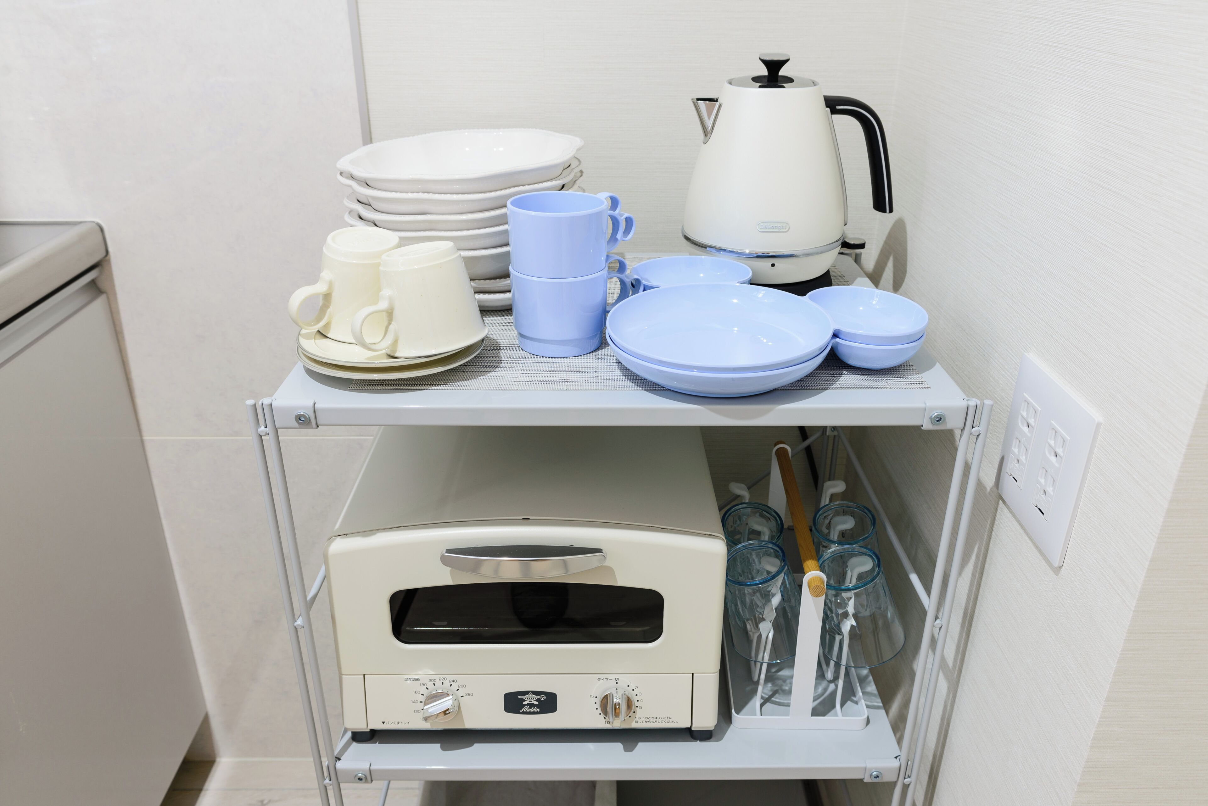 A kitchen area with a stove, coffee maker, and various dishes and cups.