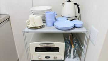 A kitchen area with a stove, coffee maker, and various dishes and cups.