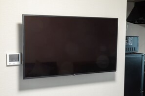 A flat-screen TV mounted on a wall with a control panel to the left. - Experience Sapporo (Sapporo)