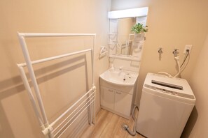 A bathroom with a white radiator, a sink, a mirror, and a small white appliance, likely a heater or dehumidifier. - Experience Sapporo (Sapporo)