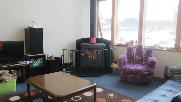 A cozy living room with a fireplace, a sofa, a coffee table, and a bookshelf. - Guest House Amigo (Toyooka)