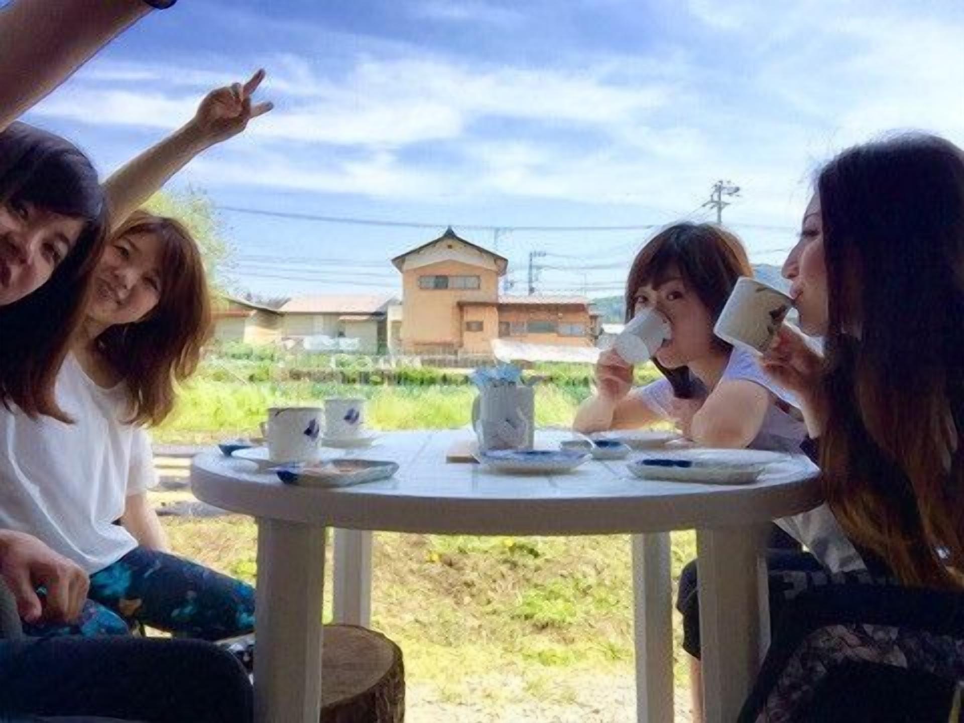 A group of people sitting around a round table outdoors with a building in the background.