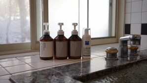 A bathroom countertop with four bottles of lotion and a soap dispenser. - Winds (Tateshina)