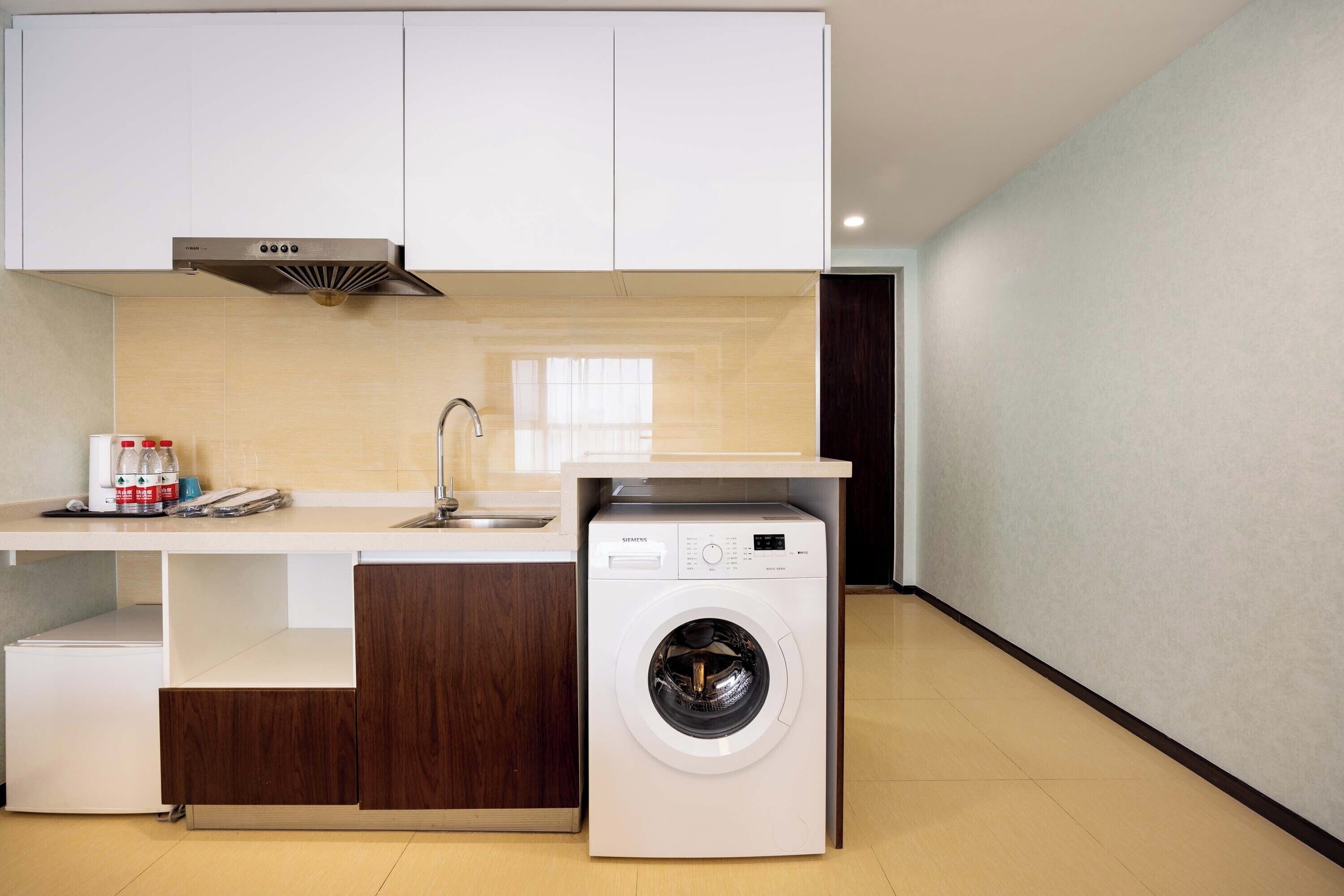 A compact kitchen with a washing machine, a sink, and a coffee maker.