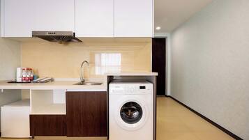 A compact kitchen with a washing machine, a sink, and a coffee maker.