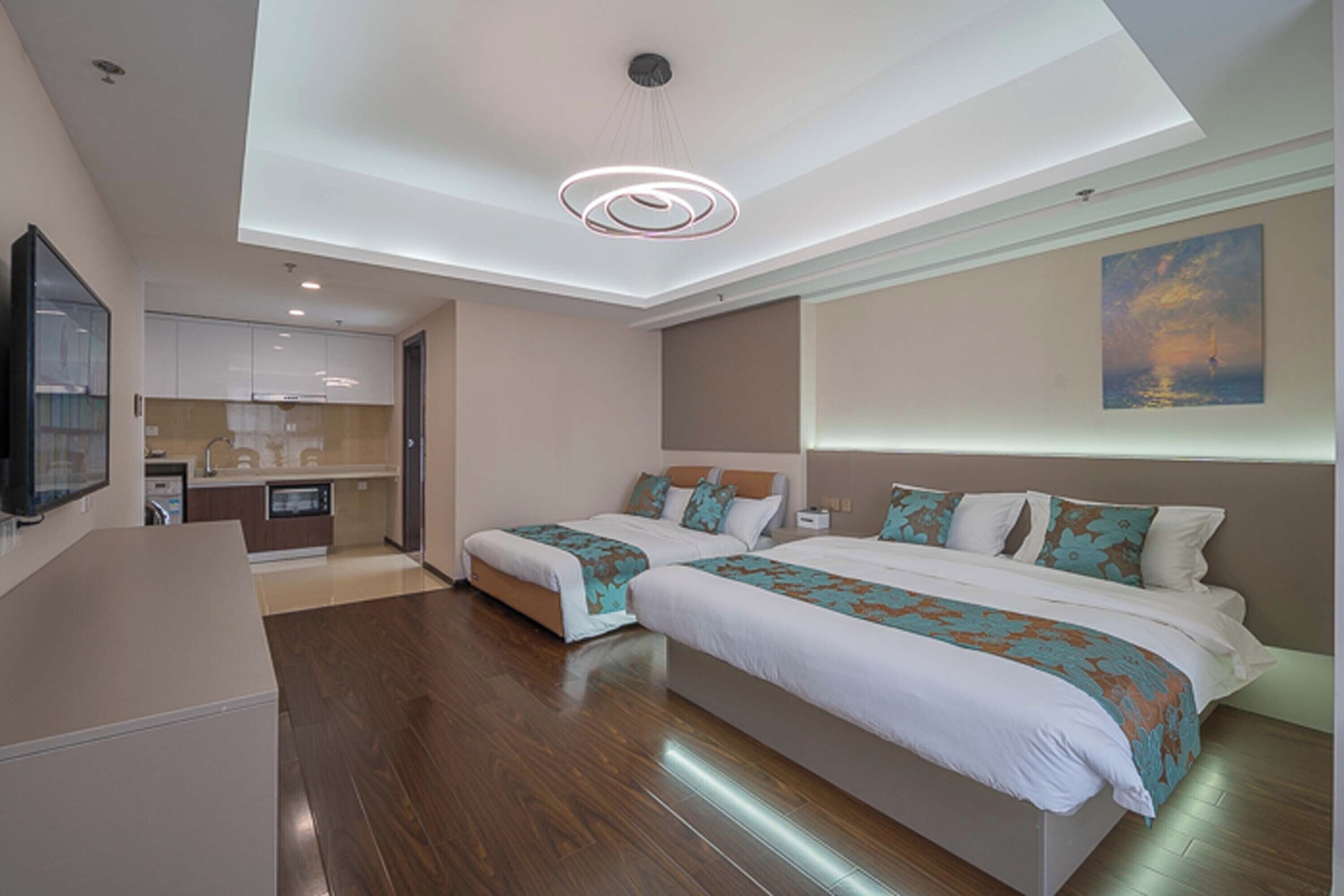 Una habitación de hotel moderna con dos camas, una zona de cocina y un ventanal grande.