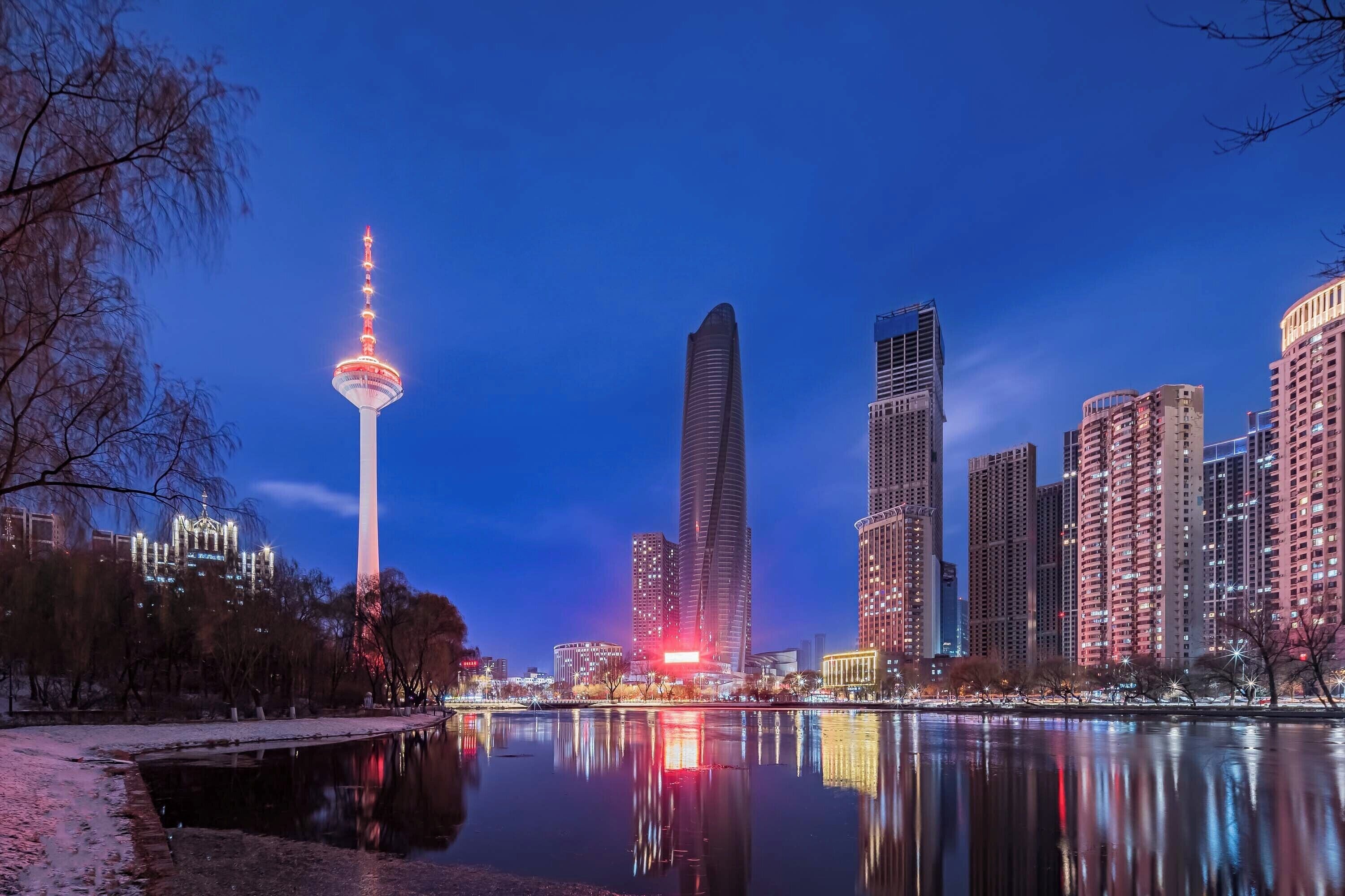 A cityscape with a prominent tower and modern buildings along a waterfront.