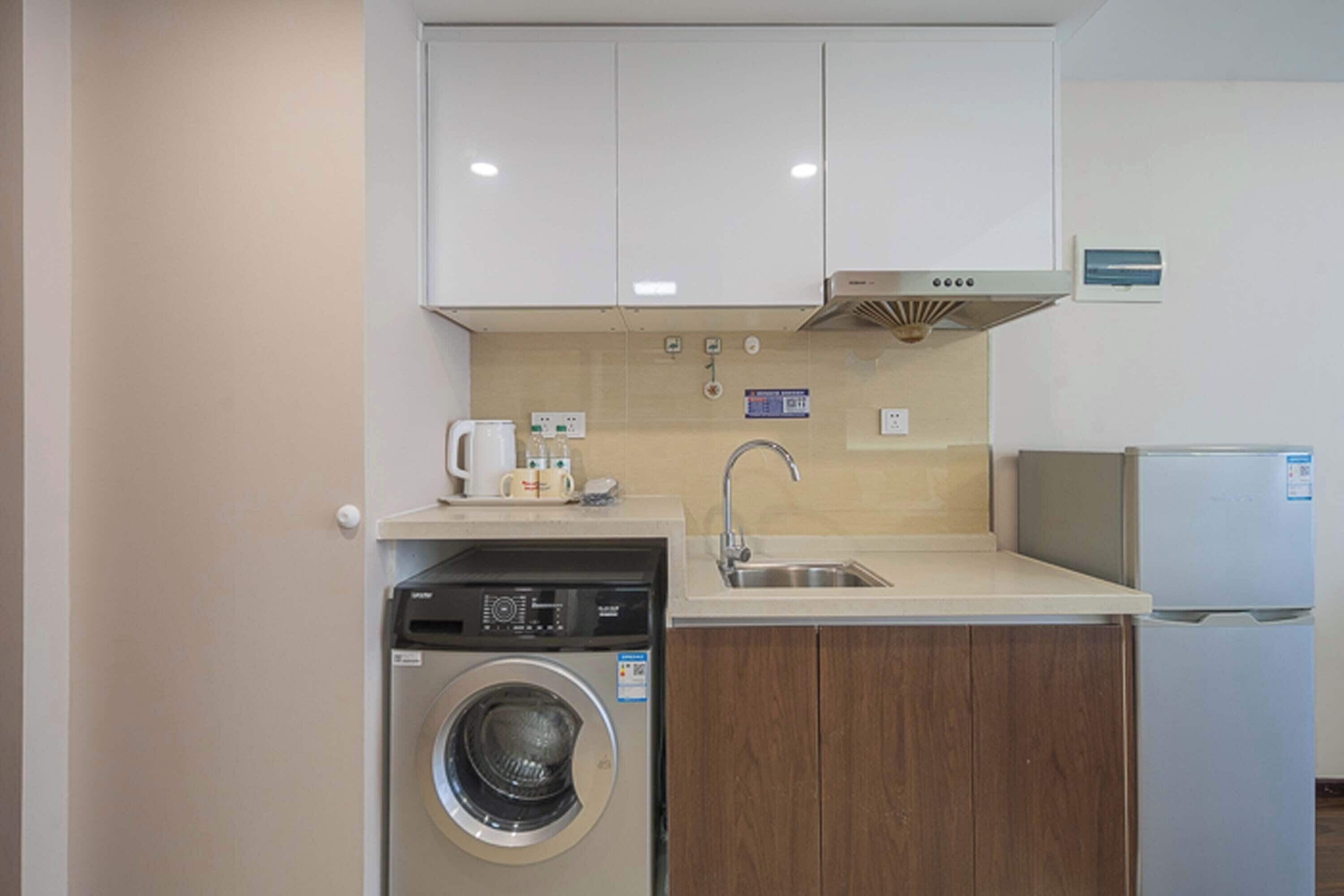 A compact kitchen with a washing machine, a coffee maker, and a refrigerator.