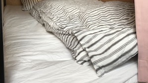 A bunk bed with a striped blanket and pillow, wooden walls, and a small light fixture. - Hostel und Kitchen Goto Base <goto, Nakadorijima> (Shinkamigoto)