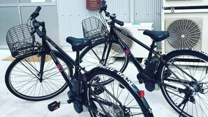 Two bicycles parked in front of a building with air conditioning units and a mailbox. - Hostel und Kitchen Goto Base <goto, Nakadorijima> (Shinkamigoto)