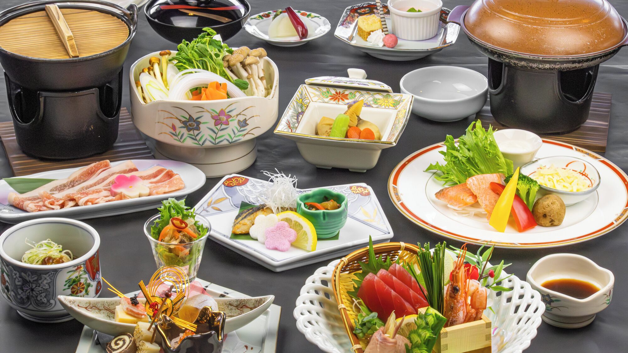 A variety of Japanese dishes including sushi, sashimi, and tempura, served on traditional ceramic and porcelain plates.