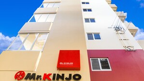 A building with a Mr. Kinjo sign, multiple windows, and a clear blue sky. - Mr.kinjo in Arcade Ange Miona (Naha)