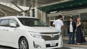 Una camioneta blanca estacionada frente a un edificio con un letrero que dice 'International Departures'.