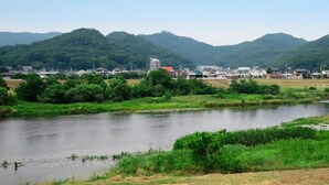 A riverside view with a building in the background and mountains in the distance. - Business Hotel New Daiei (Ashikaga)