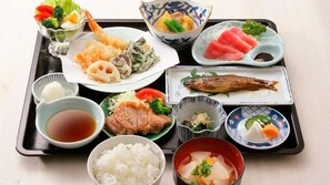 Una bandeja con diversos platos japoneses, como sushi, sashimi y arroz.