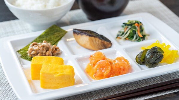 Une assiette rectangulaire blanche sur laquelle sont présentés divers plats japonais.