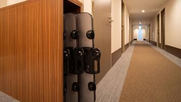 A hotel hallway with a wooden panel wall, a luggage trolley, and a carpeted floor.