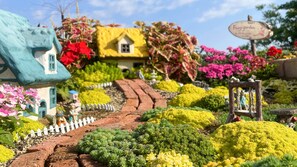 A miniature garden with a winding path, colorful flowers, and a small house. - K's Fun Garden Inn Nakijin (Nakijin)