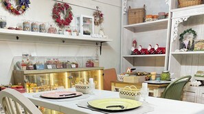 A dining area with a table set for two, a display of decorative items, and shelves with various objects. - K's Fun Garden Inn Nakijin (Nakijin)