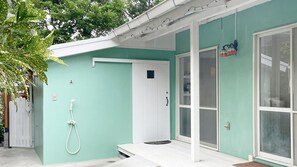 A house with a teal exterior, a white door, a glass door, and a white porch. - K's Fun Garden Inn Nakijin (Nakijin)